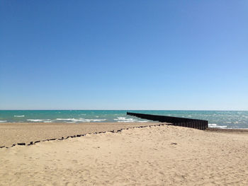 Scenic view of beach against clear blue sky