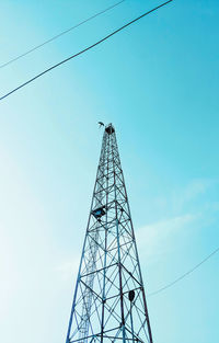 Low angle view of electricity pylon against clear blue sky