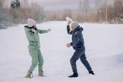 Happy couple playing winter game in forest outdoors. love and leisure concept.