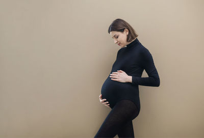 Side view of young woman standing against wall