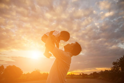 Side view of silhouette man holding orange sky