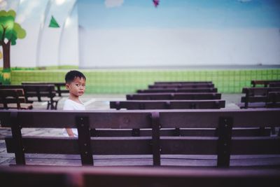 Portrait of boy looking away while sitting on bench