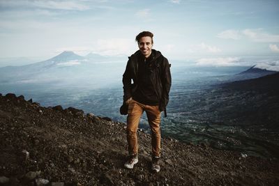 Portrait of young man hiking on mountain against sky