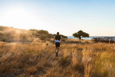 Rear view of a man jogging in the nature against clear sky