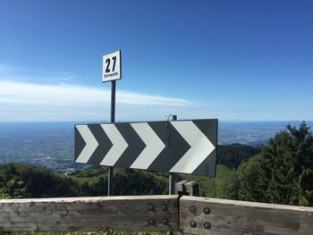 Information sign on road by sea against sky