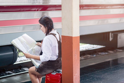 Side view of young woman sitting on book