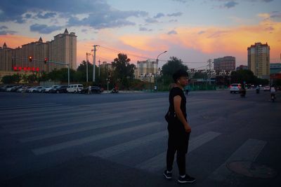 Full length of man standing on street against sky during sunset