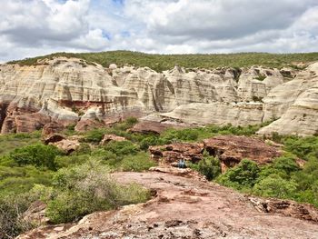 Rock formations on landscape against cloudy sky