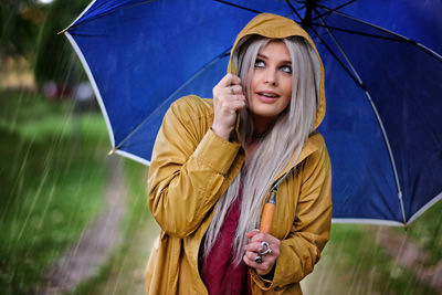 Portrait of young woman holding umbrella in rain