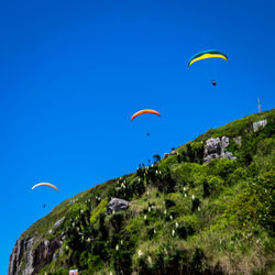 Woman paragliding against clear blue sky