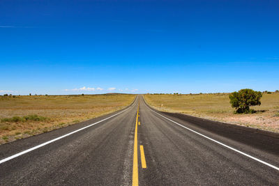 Road passing through landscape against blue sky