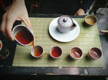 Cropped image of person pouring chinese tea in cup on table