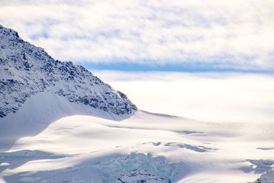 Scenic view of snowcapped mountains against cloudy sky