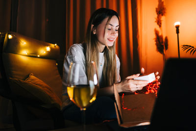 Young woman using phone while sitting on table