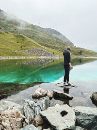 Rear view of man standing by lake