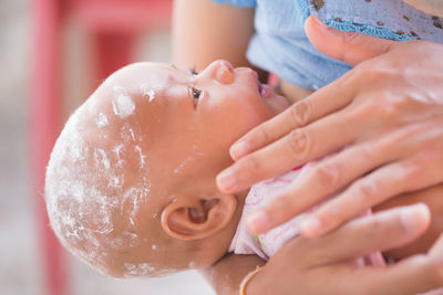 Midsection of woman feeding toddler son at home