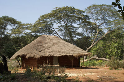 Hut by trees against sky