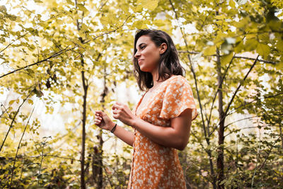 Smiling woman standing amidst trees in forest