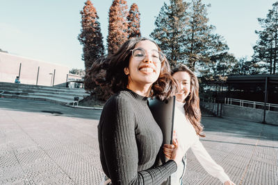 Portrait of smiling female friends walking at college campus