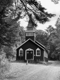 House amidst trees and plants in forest against sky