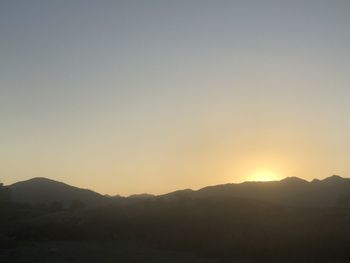 Scenic view of silhouette mountains against clear sky during sunset