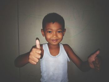 Portrait of smiling boy standing against wall