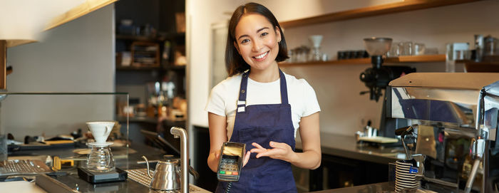 Portrait of young woman standing in cafe