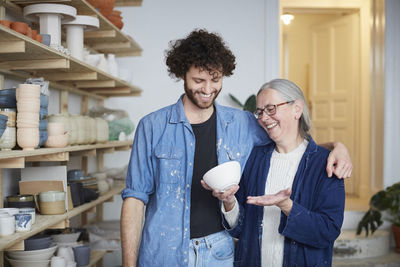 Smiling man and woman looking at bowl in pottery class