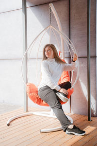 Full length of young woman sitting on porch swing