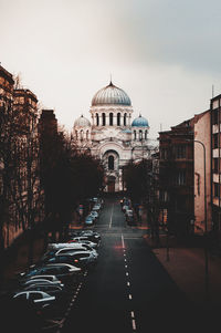 Road amidst buildings in city against sky