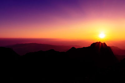 Scenic view of silhouette mountains against orange sky