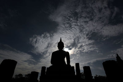 Low angle view of silhouette buddha statue at wat muang against sky