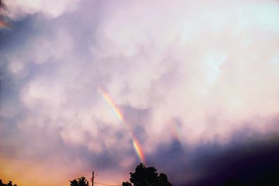 Low angle view of rainbow over trees against sky