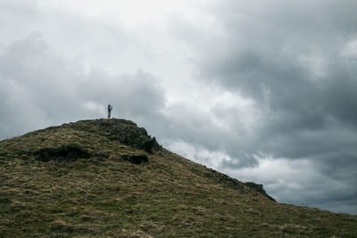 Low angle view of man standing on mountain against sky