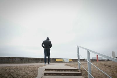 Rear view of man walking against clear sky