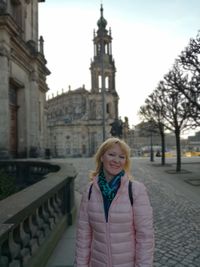 Portrait of smiling mature woman standing on street against cathedral in town