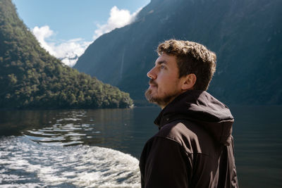 Side view of young man looking away against mountains