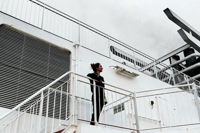 Man standing on staircase in city against sky