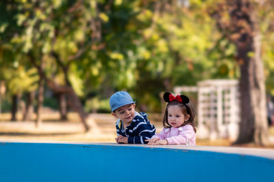 Siblings on retaining wall in park