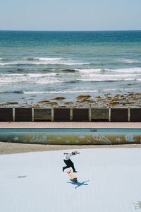 High angle view of man skateboarding at park by sea