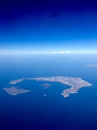 Aerial view of island amidst sea against blue sky