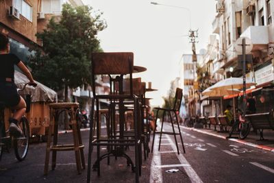 Street in the city with chairs placed in the middle in front of a cafe blocking the traffic 
