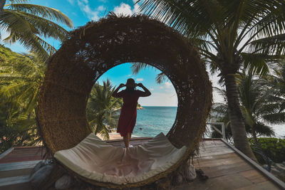 Man standing by palm tree against sea