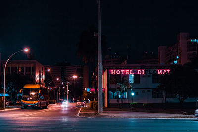 Illuminated street amidst buildings in city at night
