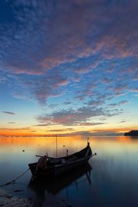 Silhouette boats moored on sea against sky during sunset