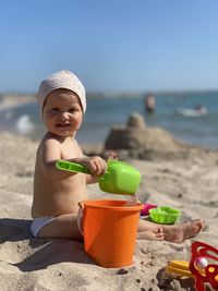 Boy wearing sunglasses on beach against sky