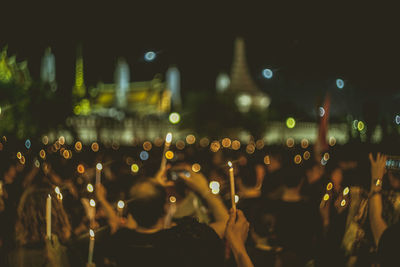 Defocused image of people with lit candles at music concert