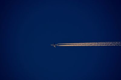 Low angle view of airplane flying against clear blue sky