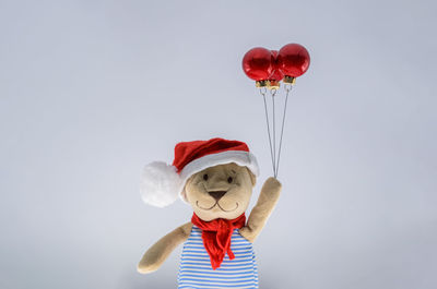 Teddy bear santa claus holding red baubles ornament set as balloon. minimal holiday concept.