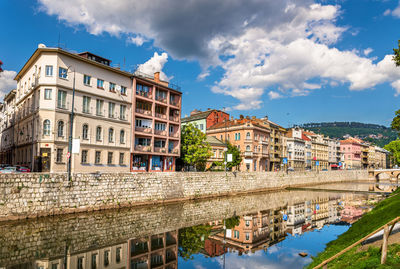 Residential buildings by river against sky